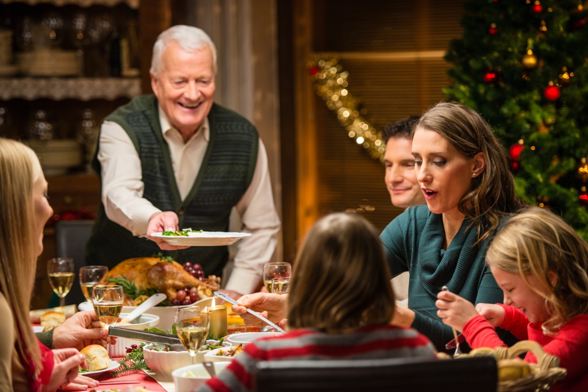 A family enjoying their Christmas dinner. Grandfather passing dish to grandson